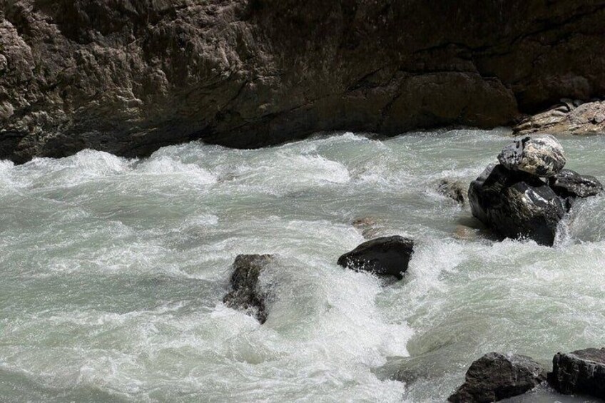A turbulent river with rocks and a rocky cliff. 3