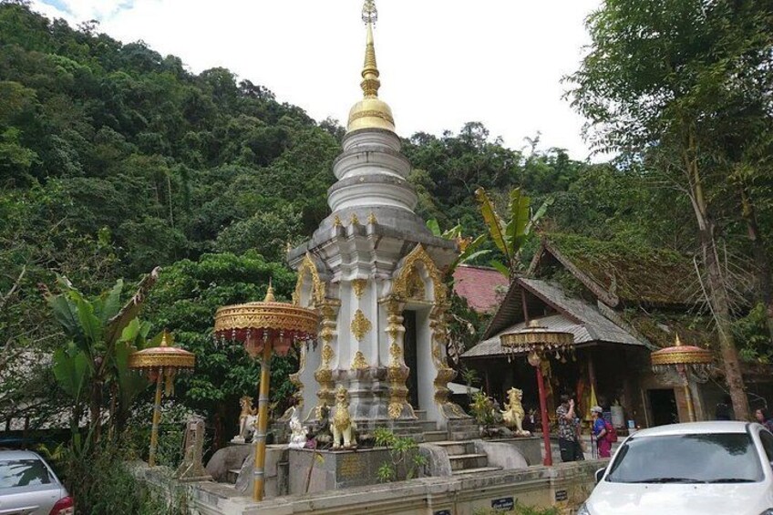 A temple with a golden spire, surrounded by lush greenery and traditional structures. 4