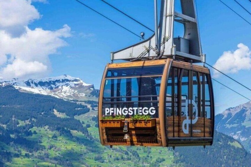 A cable car with 'PFINGSTEGG' written on it, suspended above a mountainous landscape. 4