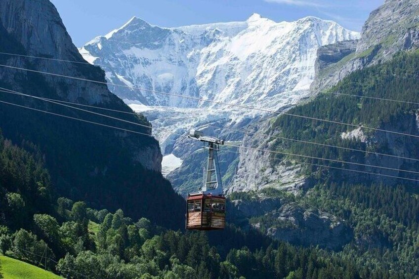 A cable car in a mountainous landscape with snow-capped peaks and dense forests. 1