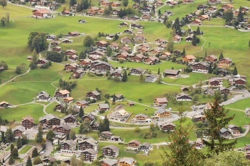 A village with houses, green fields, and a mountain in the background. 2