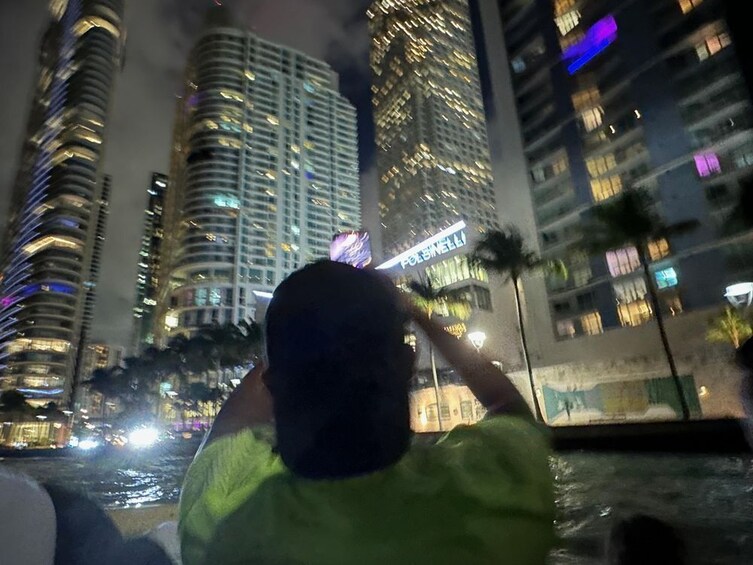 Une vue nocturne d’une ville, avec des gratte-ciel illuminés et une personne au premier plan. 5