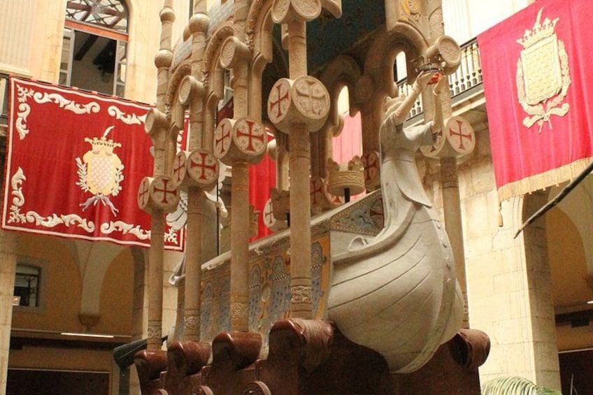 A large ornate ship sculpture with a red and gold banner in the background. 2