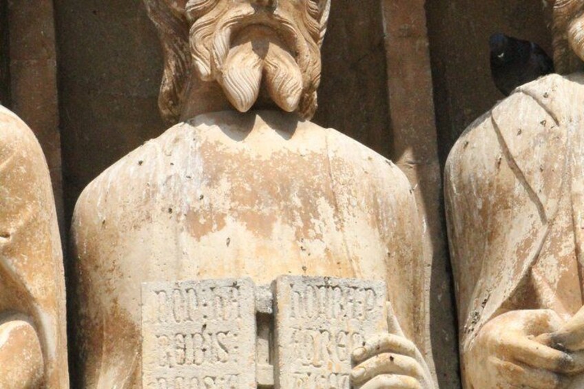 A weathered stone statue with inscriptions, part of a larger structure. 2