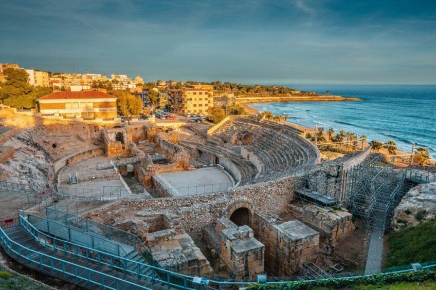 An ancient amphitheater with a stage, seating, and a surrounding wall. 1