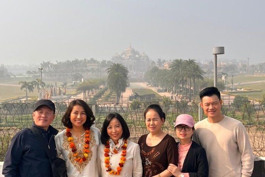 A group of people standing in a park with a temple in the background. 2