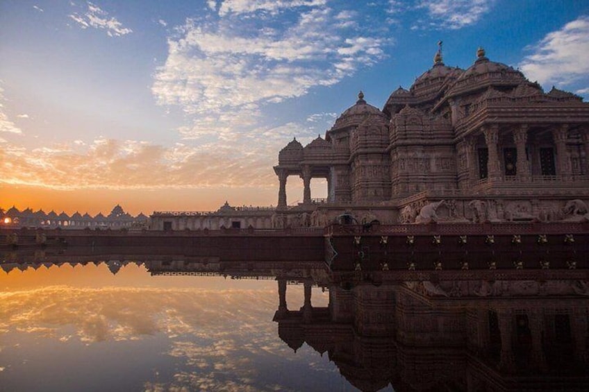 A temple with intricate architecture, a reflection in the water, and a sunset sky. 1