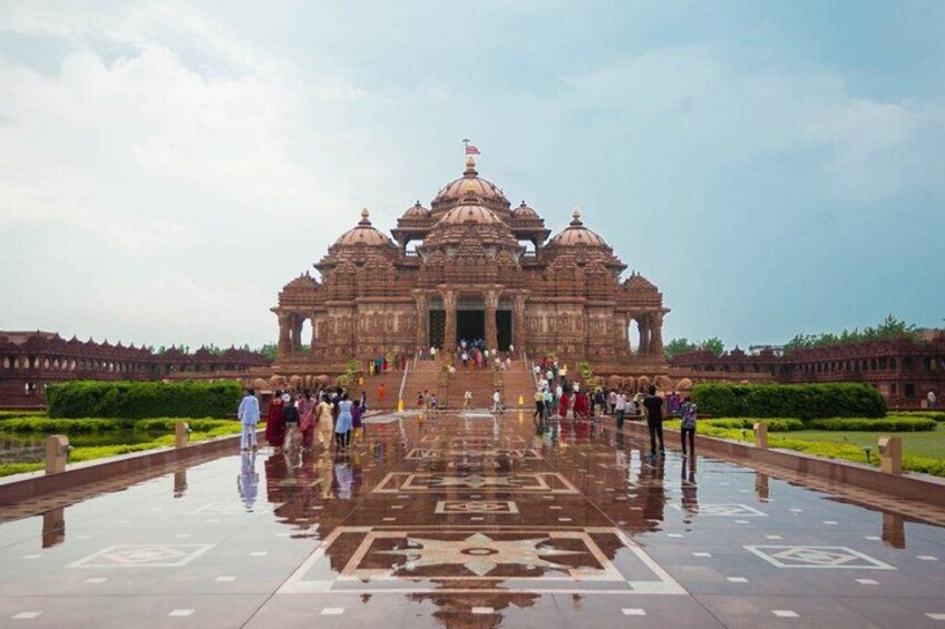 A large, ornate temple with multiple domes and a central entrance, surrounded by a reflective water feature and a well-maintained garden. 3