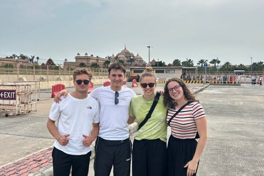 Four people standing in an open area with a temple in the background. 4