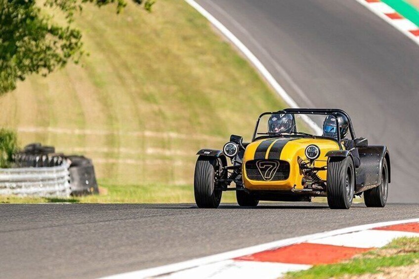 A yellow race car with black stripes on a race track. 2