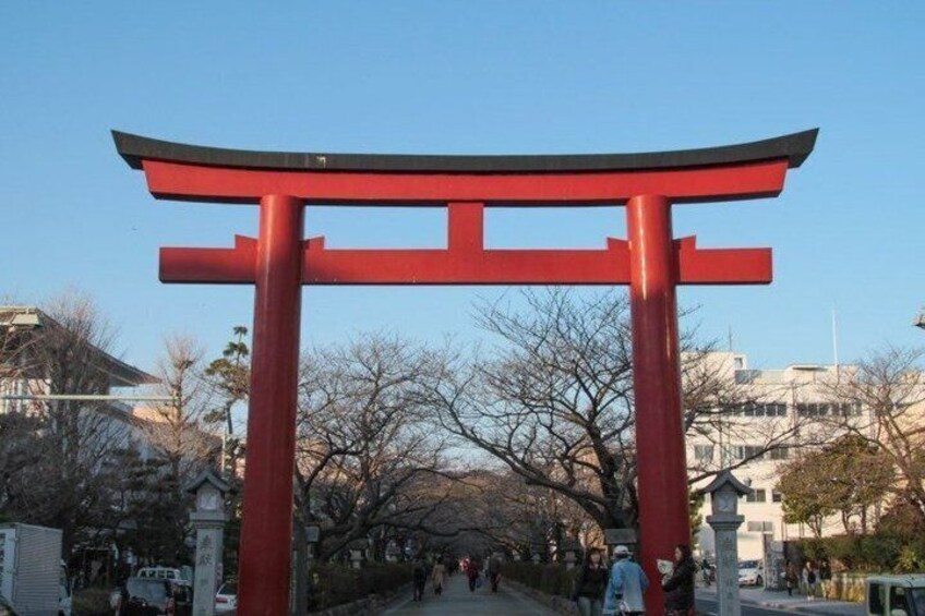 A red torii gate in a park with leafless trees and buildings in the background. 4