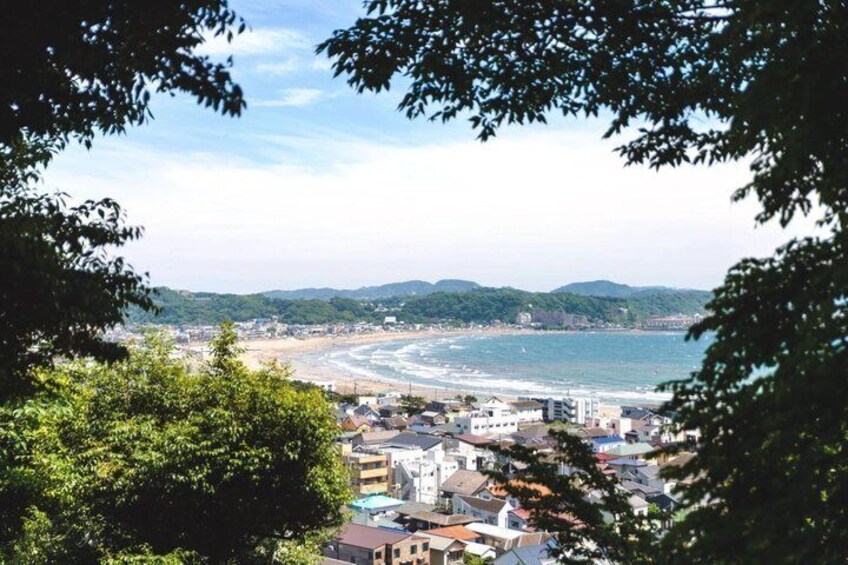 A coastal cityscape with a beach, buildings, and hills in the background. 3