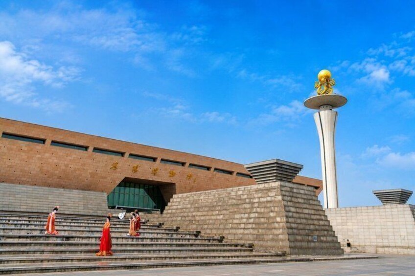 A building with a large golden statue on top, steps leading up to it, and a clear blue sky. 5