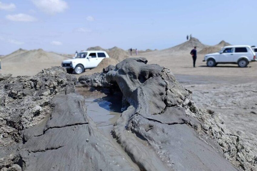 A muddy terrain with a large rock formation and vehicles. 4