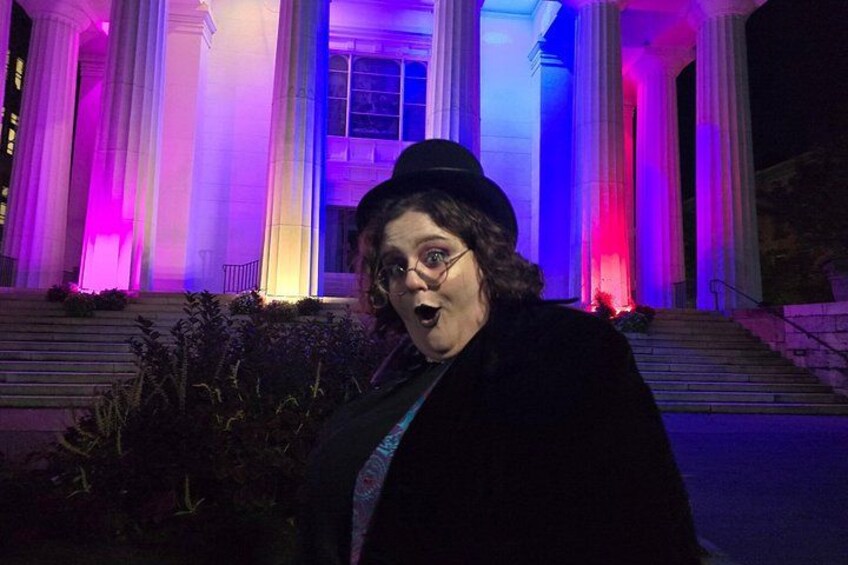A person standing in front of a building with illuminated columns and steps. 1
