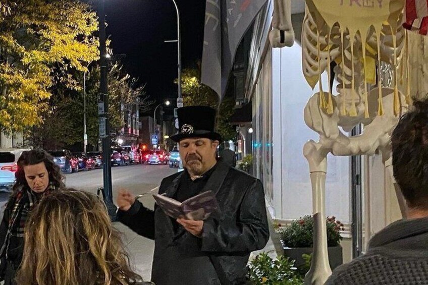 A person reading a book on a street at night. 5
