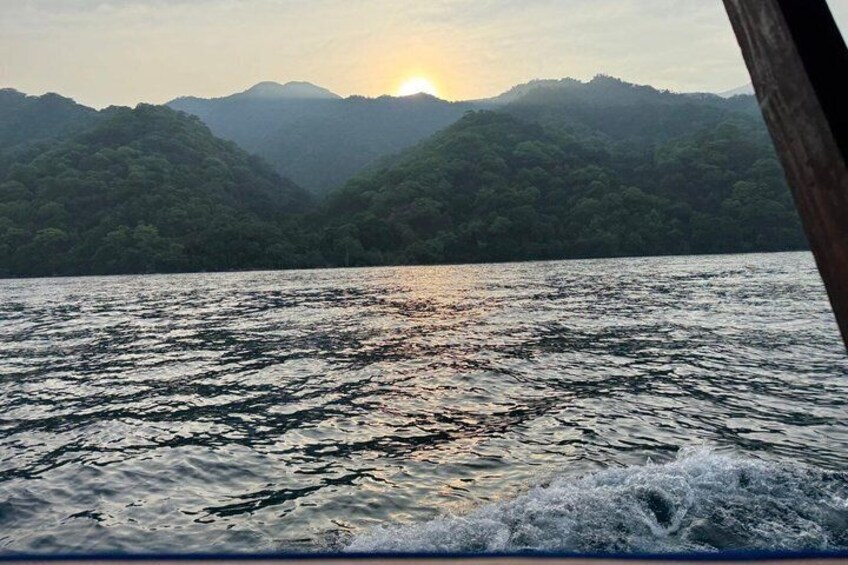 A body of water with waves, a wooden structure, and a mountain range in the background. 5
