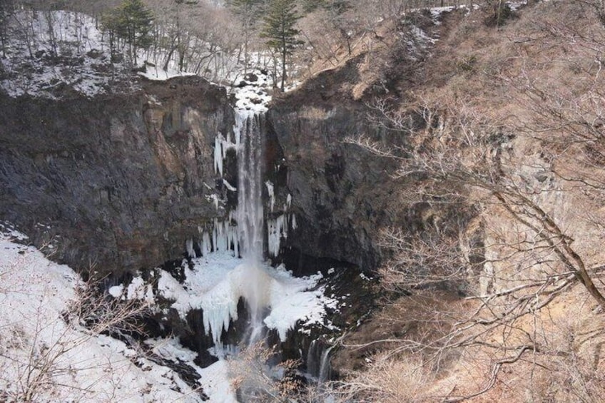 A waterfall cascading over a rocky cliff into a snow-covered valley. 4