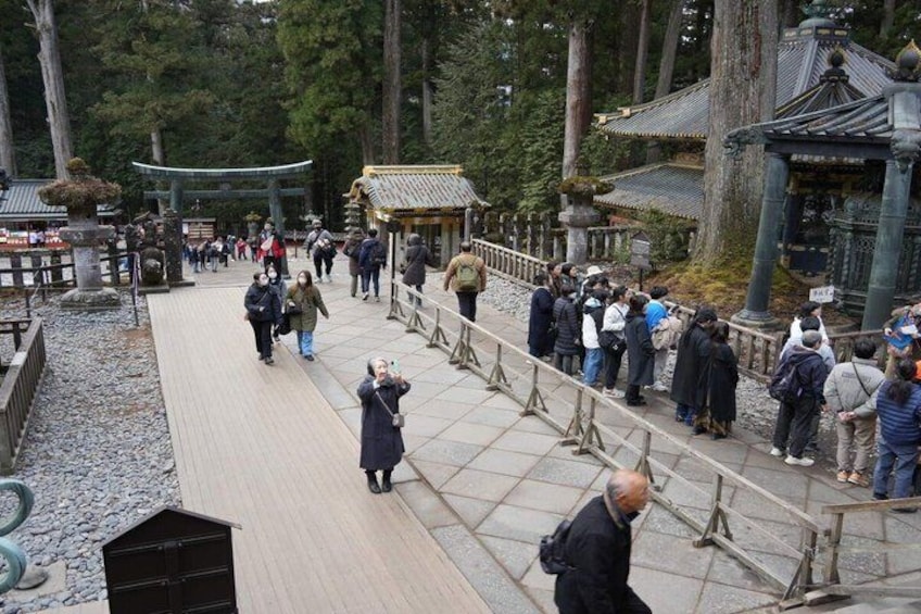 A traditional Japanese temple with visitors walking on a wooden pathway. 1