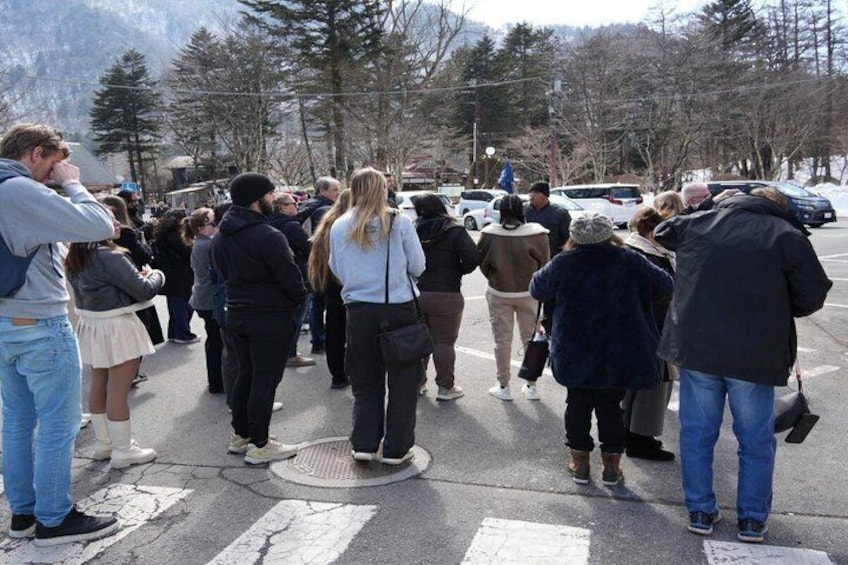 A group of people standing on a street, some looking at a white van. 5