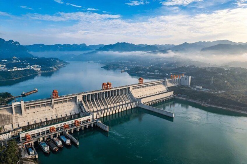 A hydroelectric dam with multiple gates, a lock system, and boats docked at the marina. 1