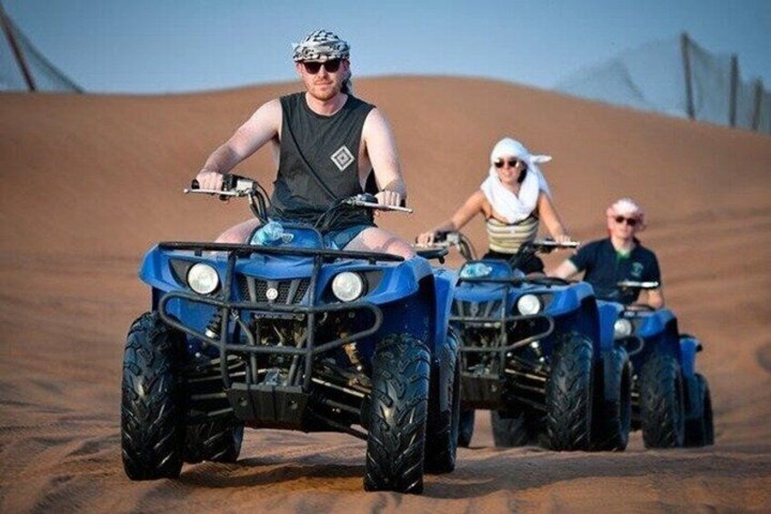 A person riding an ATV on a sandy terrain. 1