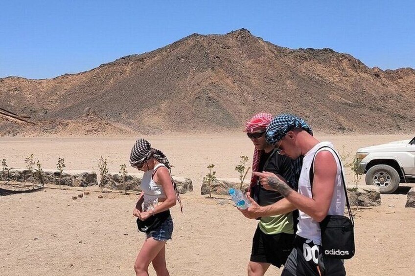 A desert landscape with a mountain in the background, a white vehicle, and three people. 5