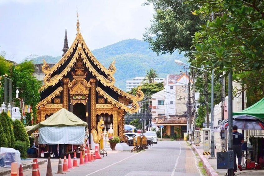 A traditional Thai temple with a golden roof, surrounded by trees and buildings. 4