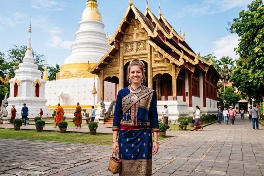 A person in traditional attire standing in front of a temple with golden roofs and white spires. 2