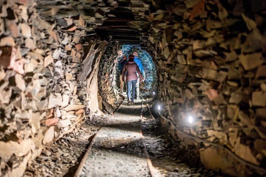 A person walking through a stone tunnel with a flashlight. 4