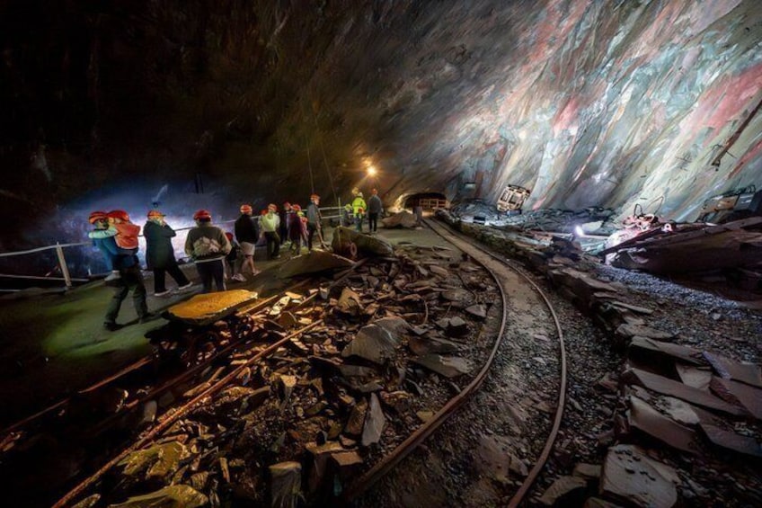 An underground tunnel with people, debris, and mining equipment. 5
