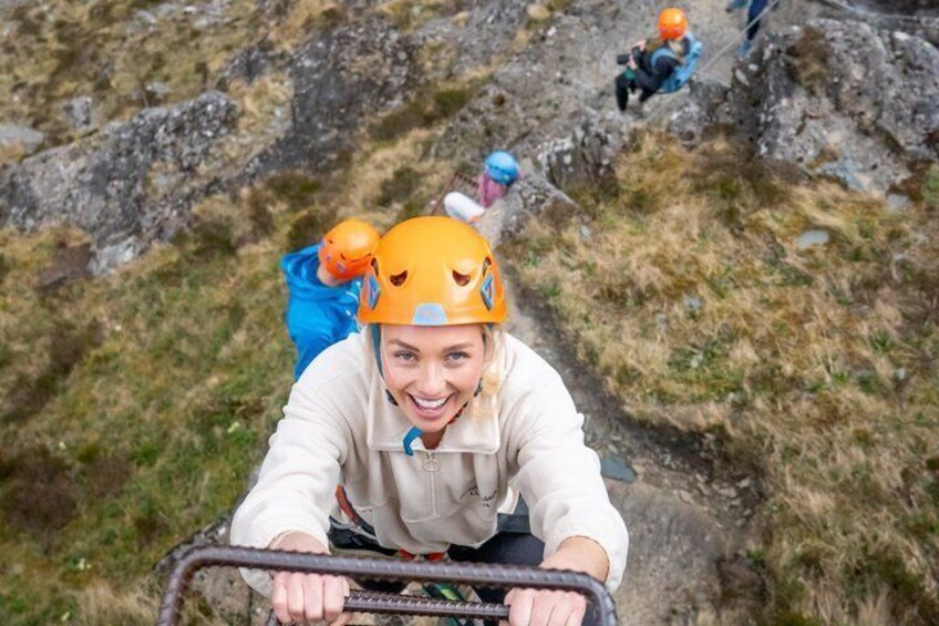 A person in a helmet and jacket climbing a rocky path with another person in the background. 1