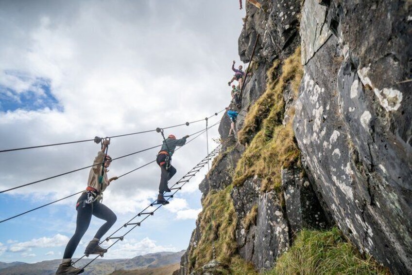 People rappelling down a cliff, a rope bridge, and a mountainous landscape. 4