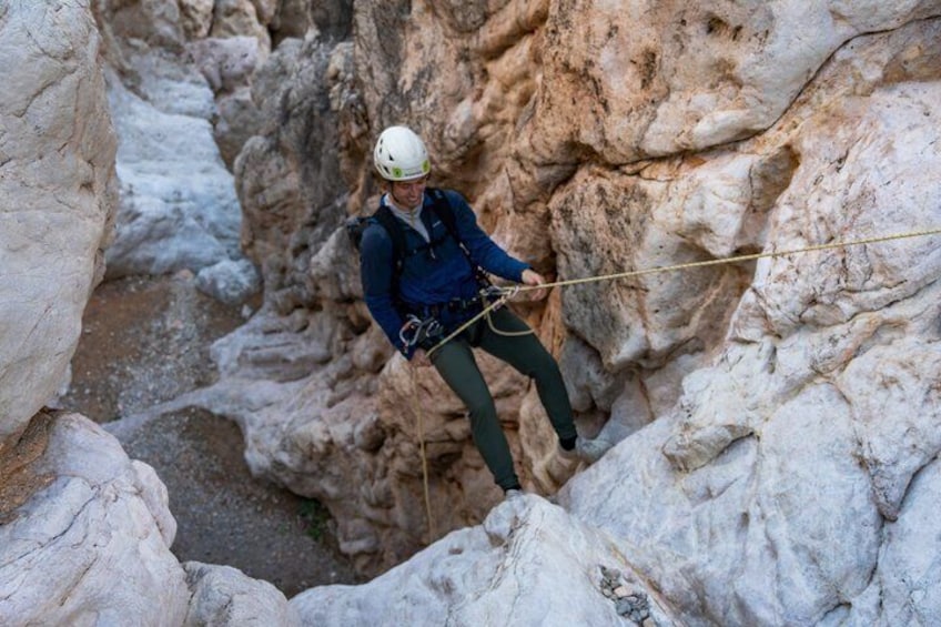 A person climbing a rocky cliff with a rope. 2
