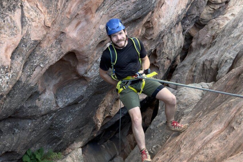 A person climbing a rocky cliff with safety harness and ropes. 2