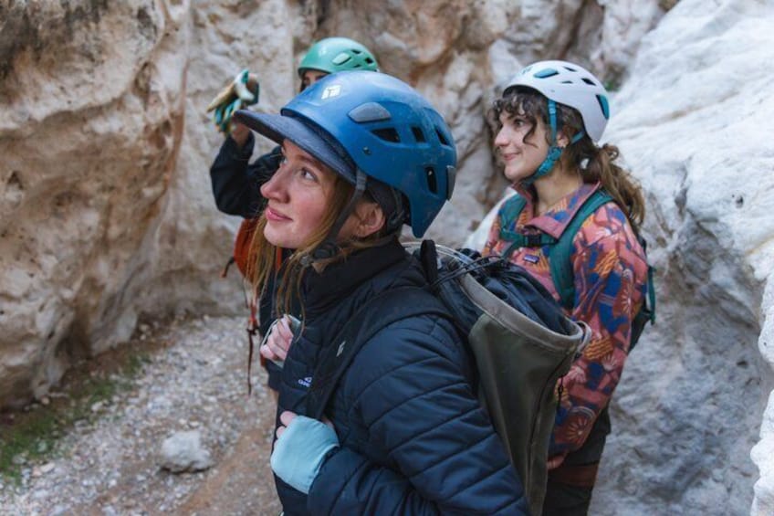 Two people wearing helmets and backpacks, standing in a rocky terrain. 5