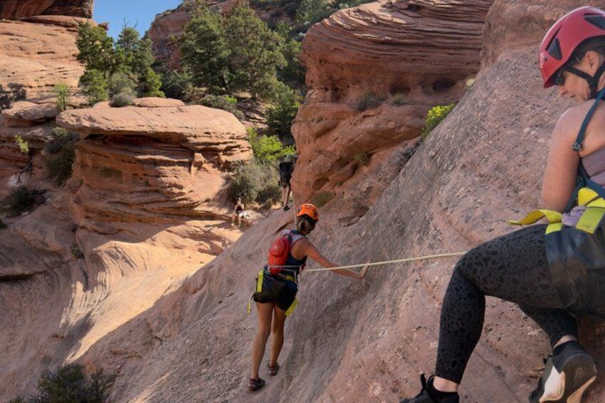 A person climbing a rocky mountain with a rope, wearing a helmet and harness. 5