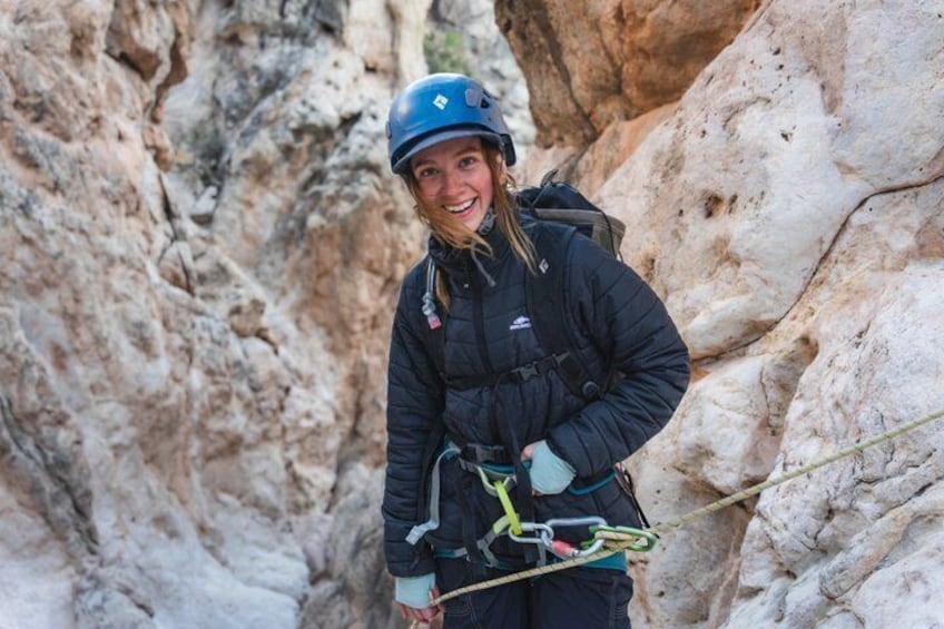 A person climbing a rocky cliff with a helmet and harness. 4