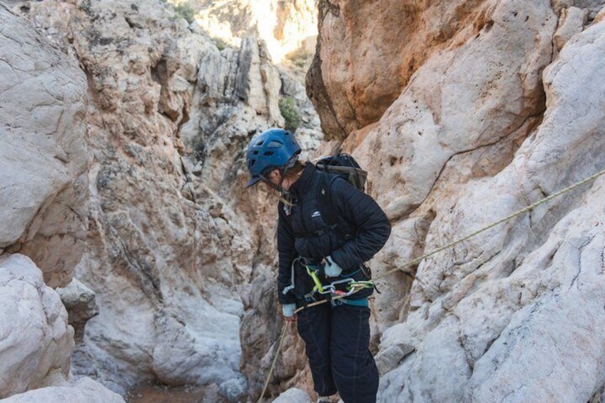 A person climbing a rocky canyon with a helmet and harness. 3