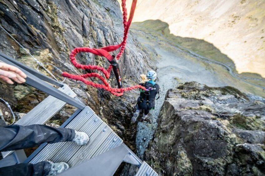 A person rappelling down a rocky cliff with a rope. 1