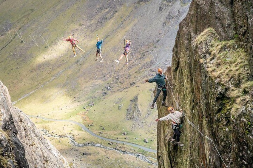 A group of people performing a high-altitude rope course with a valley below. 5