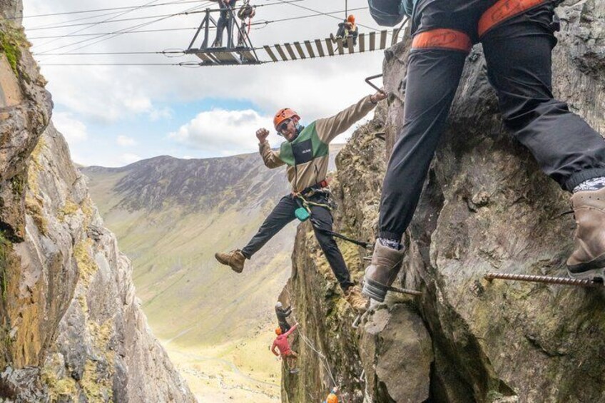 A person rappelling down a rocky cliff with a harness and rope, with a mountainous landscape in the background. 5