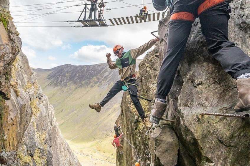 A person rappelling down a rocky cliff with a harness and rope, with a mountainous landscape in the background. 3