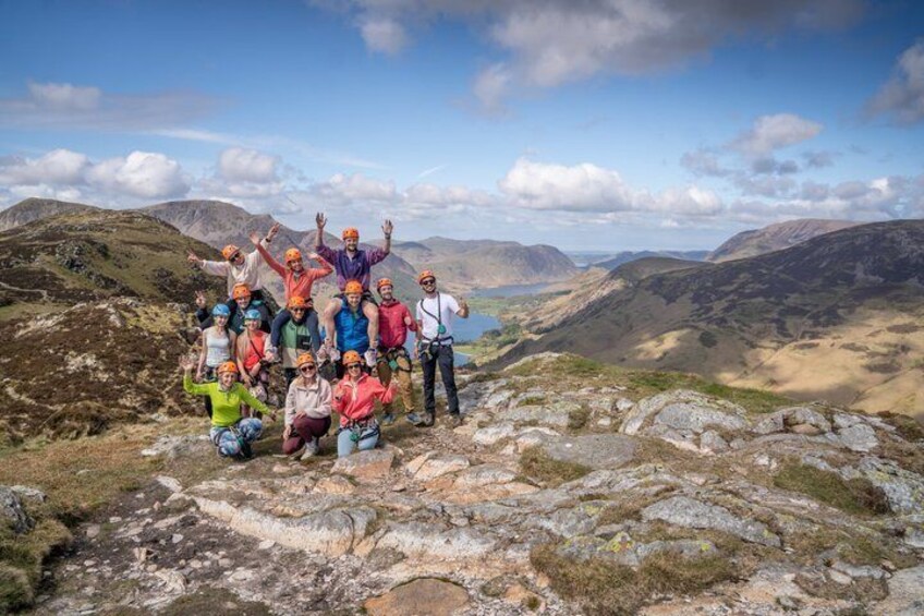 A group of people on a rocky mountain landscape with a lake in the distance. 3