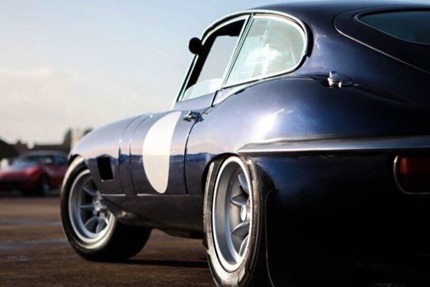 A vintage car with a white racing stripe, chrome wheels, and a classic design. 4