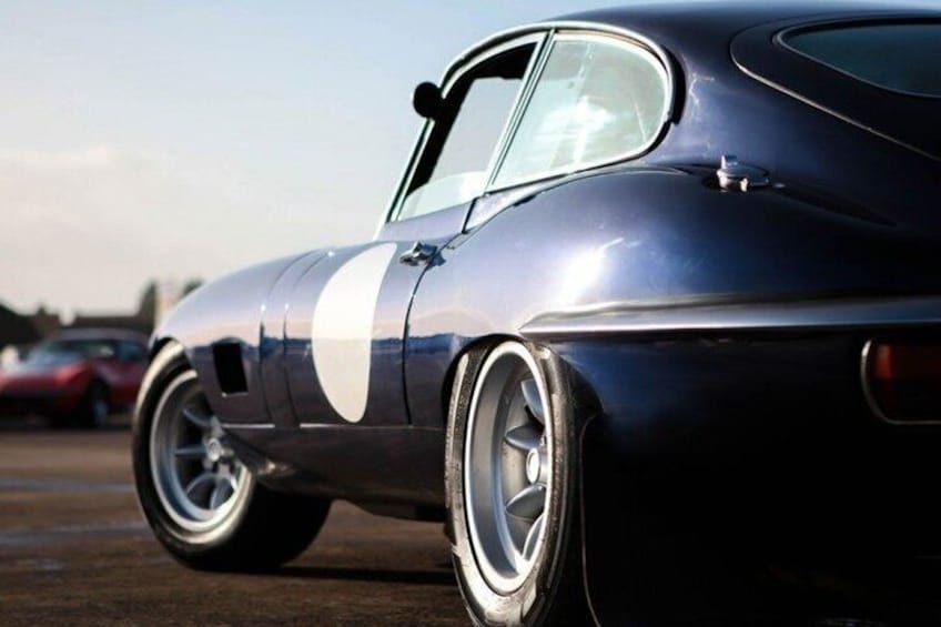 A vintage car with a white racing stripe, chrome wheels, and a classic design. 4