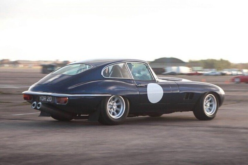 A vintage sports car parked on a racetrack. 3