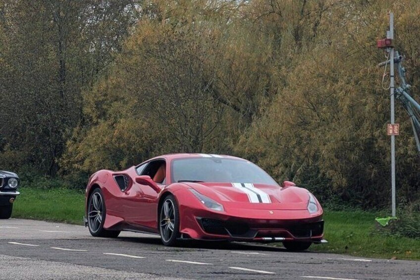 A red sports car parked on a road with trees in the background. 2