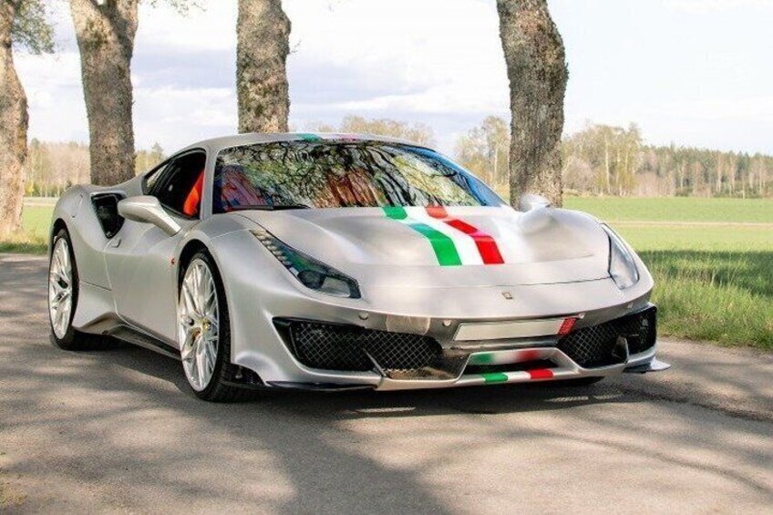 A silver sports car with a colorful stripe design parked on a road with trees in the background. 5