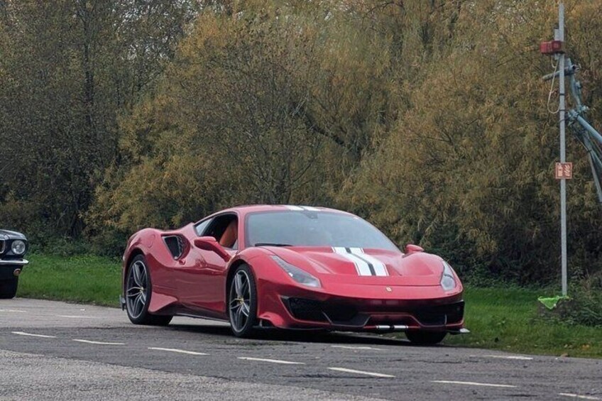 A red sports car parked on a road with trees in the background. 3